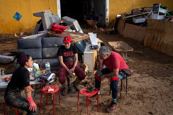 Members of a theatre company sit with their muddy belongings after the floods in the outskirts of Valencia, Spain, Friday, Nov. 8, 2024. (AP Photo/Emilio Morenatti)