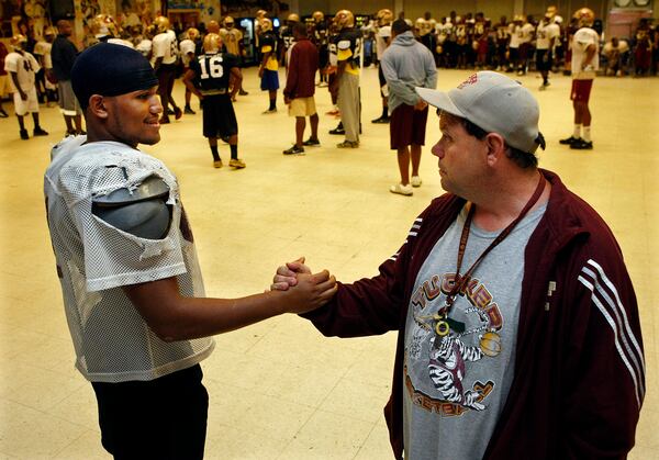 091014 Tucker - TELL ME SOME HISTORY BUD-  Bud King,43, the man behind the Tucker program, shakes hands with offensive guard # 62 Chris Smith as they talk team history during football practice inside the Tucker High School cafeteria on Tuesday, Oct.14, 2009. King, a walking encyclopedia of Tucker players and coaches, has been at the school since 1989. Smith was asking King what his most memorable moments were in Tucker football history.    Curtis Compton, ccompton@ajc.com