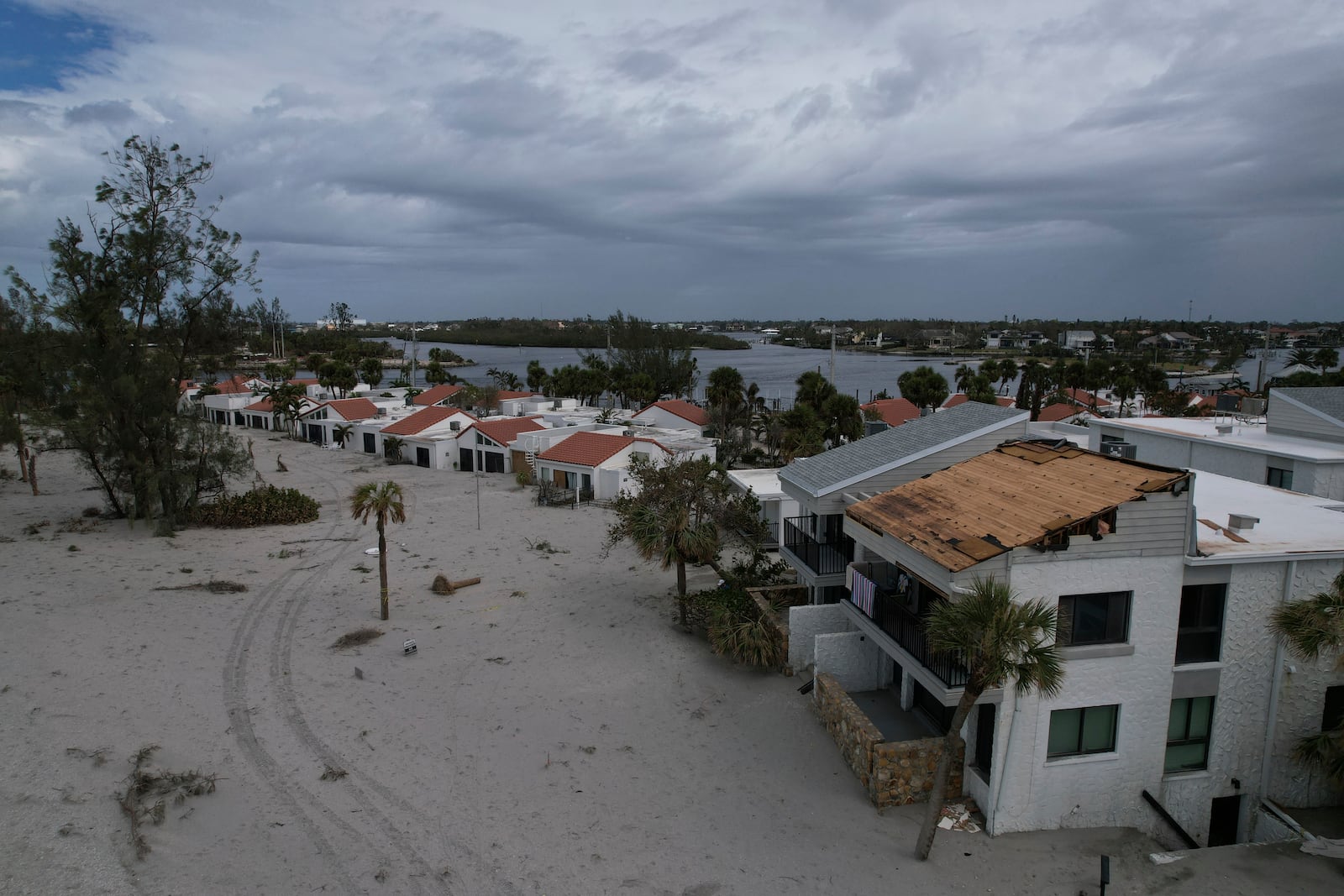 The damaged roof of Ron and Jean Dyer's beachfront condo at Bahia Vista Gulf is seen alongside the sand-swamped Jetty Villas, after the passage of Hurricane Milton, on the island of Venice, Fla., Friday, Oct. 11, 2024. (AP Photo/Rebecca Blackwell)