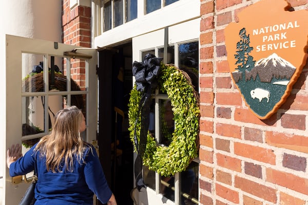 A visitor enters Plains High School, which featured wreathes on the entrance in honor of former President Jimmy Carter. (Arvin Temkar / AJC)