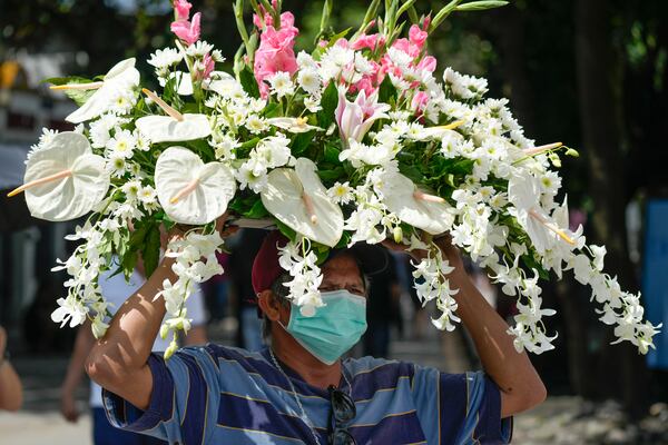 A man carries flowers at Manila's North Cemetery, Philippines as the nation observes All Saints Day on Friday, Nov. 1, 2024. (AP Photo/Aaron Favila)