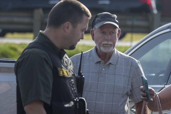 Hoschton Councilman Jim Cleveland is escorted to his car by a Jackson County Sheriff’s Department officer following a City Council meeting where members of the community urged his resignation at the Hoschton Historic Train Depot on Monday, May 6, 2019. 