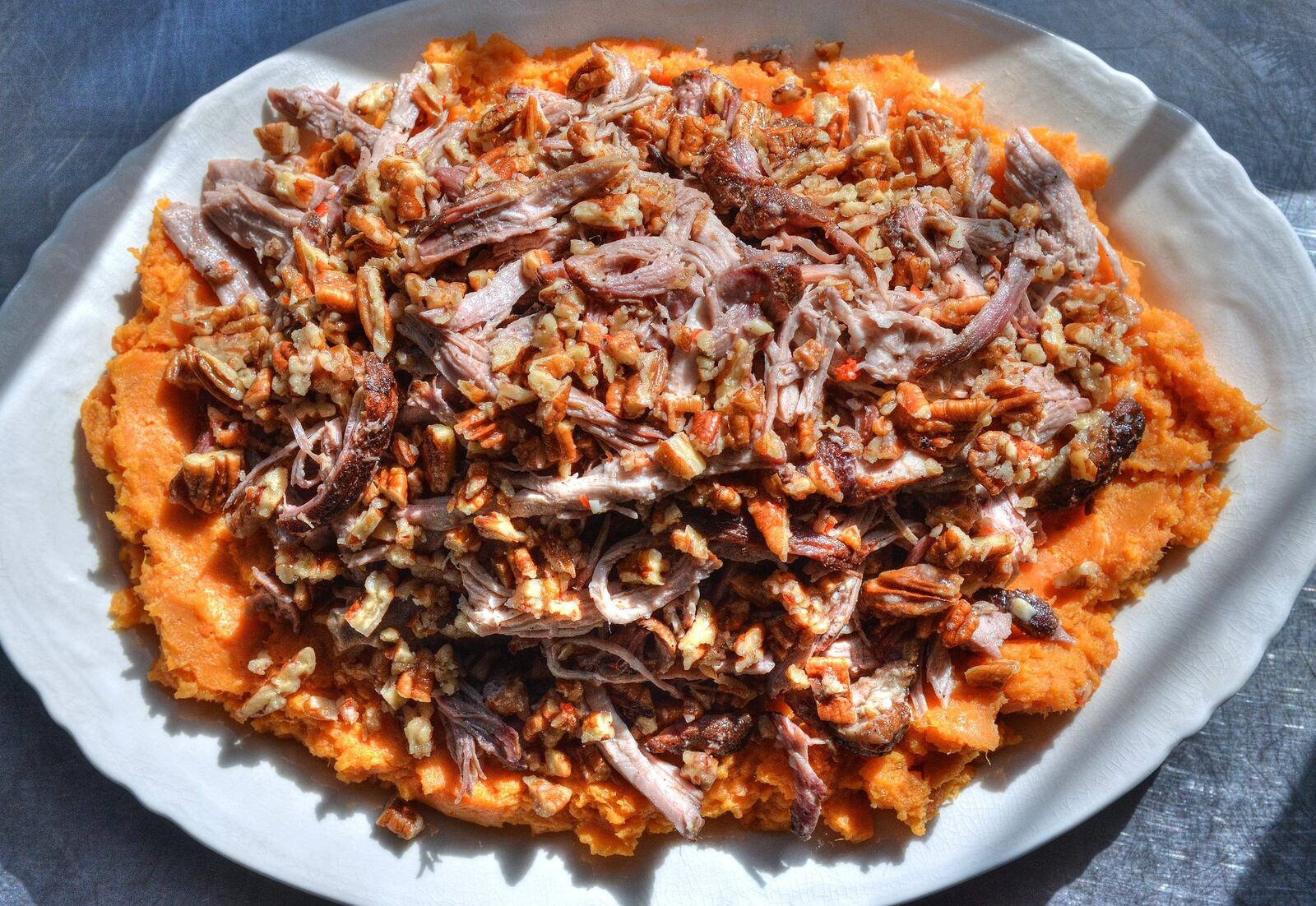 Hudson Rouse, the chef at Rising Son in Avondale Estates, shared his recipe for Pulled Pork with Smashed Sweet Potatoes and Pecans. (PHOTO CONTRIBUTED BY CHRIS HUNT; STYLING BY WENDELL BROCK)