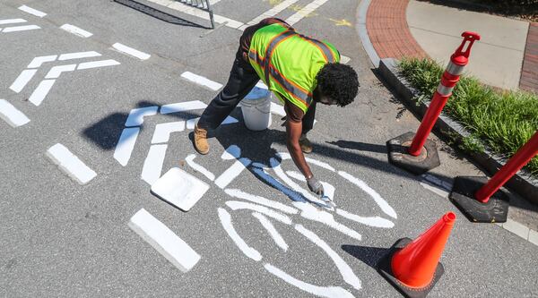 Glenn Hickey paints a stretch of bike lanes on Ferst Drive on the campus of Georgia Tech. (John Spink / John.Spink@ajc.com)