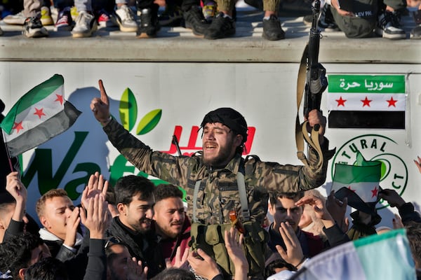 A Syrian member of the rebel group celebrates during a demonstration following the first Friday prayers since Bashar Assad's ouster, in Damascus' central square, Syria, on Friday, Dec. 13, 2024. (AP Photo/Hussein Malla)