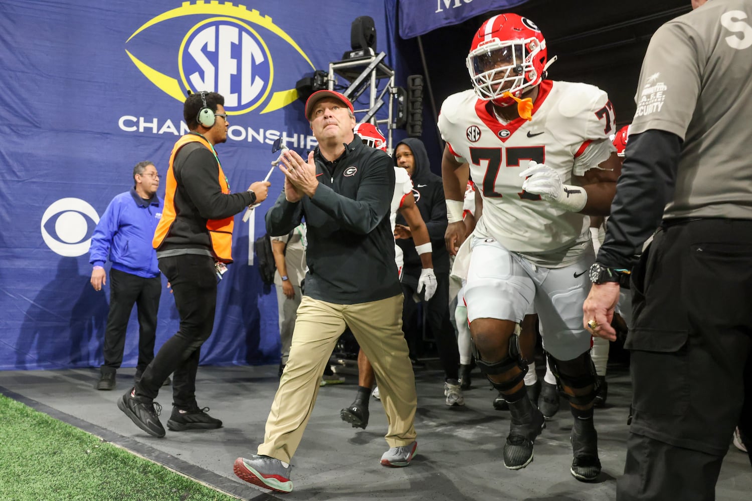 Georgia Bulldogs offensive lineman Sedrick Van Pran (77) wears the jersey number of Devin Willock, a tribute to the player who was killed in a January car crash, as he enters the field with head coach Kirby Smart before facing the Alabama Crimson Tide in the SEC Championship football game at the Mercedes-Benz Stadium in Atlanta, on Saturday, December 2, 2023. (Jason Getz / Jason.Getz@ajc.com)