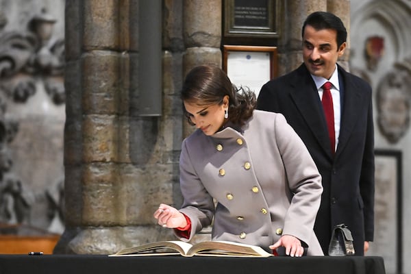 Qatar's Emir Sheikh Tamim bin Hamad al-Thani looks as his wife Sheikha Jawaher bint Hamad bin Suhaim al-Thani signing the guests book during a visit to Westminster Abbey, in London, Tuesday, Dec. 3, 2024, on the first day of their two-day State Visit to Britain. ( Justin Tallis/Pool photo via AP)