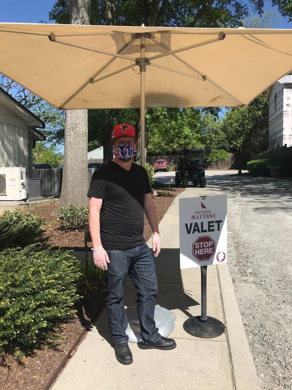 Zac Reed stands ready for curbside pickup duty at Osteria Mattone in Roswell. Normally a server at sister restaurant Coalition Food and Beverage, one day a week, Reed works at other sister restaurant, Table and Main, for the restaurant group’s Table and Aid effort to offers free food for those in need. The day that is most rewarding is the day I am at Table and Main,” said Reed. “It’s good for the soul.” LIGAYA FIGUERAS/LIGAYA.FIGUERAS@AJC.COM