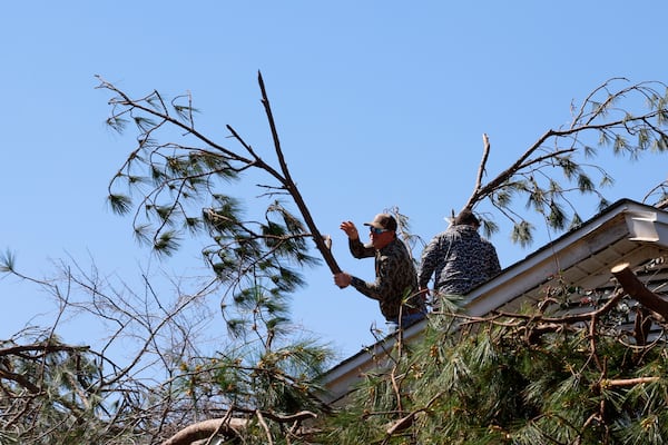 Friends and family members remove trees from a house after a tornado passed through the area Sunday, March 16, 2025, in Plantersville, Ala. (AP Photo/Butch Dill)