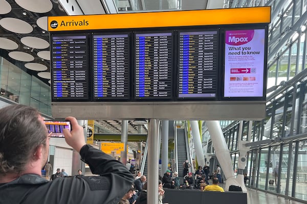 A man takes a photo of the flight information display in the arrivals hall at Heathrow Terminal 5 in London, Saturday March 22, 2025, after flights resumed at the airport. (Maja Smiejkowska/PA via AP)