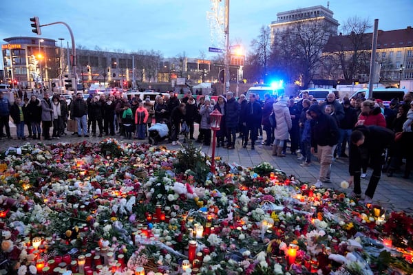 Citizens pay tribute for deaths outside St. John's Church near a Christmas Market, where a car drove into a crowd on Friday evening, in Magdeburg, Germany, Saturday, Dec. 21, 2024. (AP Photo/Ebrahim Noorozi)