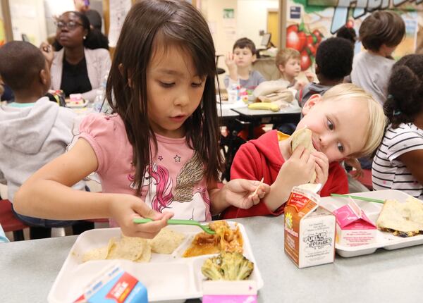 Vivian White, left, and Marston Bunting, kindergarten students, eat lunch at Burgess-Peterson Academy in Atlanta on Friday. To celebrate Earth Day, Burgess-Peterson Academy is one of about 15 Atlanta schools that used biodegradable products, such as trays and forks. EMILY HANEY / emily.haney@ajc.com