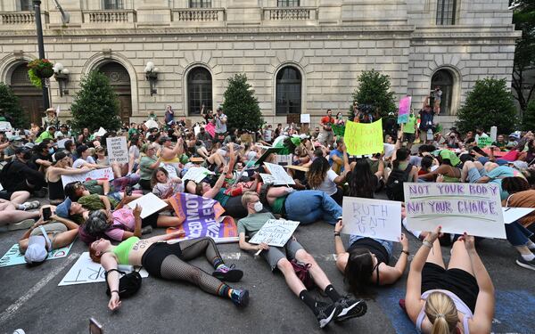 People "play dead" outside the U.S. Court of Appeals building in downtown Atlanta on June 25 to protest the Supreme Court's decision to overturn Roe v. Wade. (Hyosub Shin / Hyosub.Shin@ajc.com)