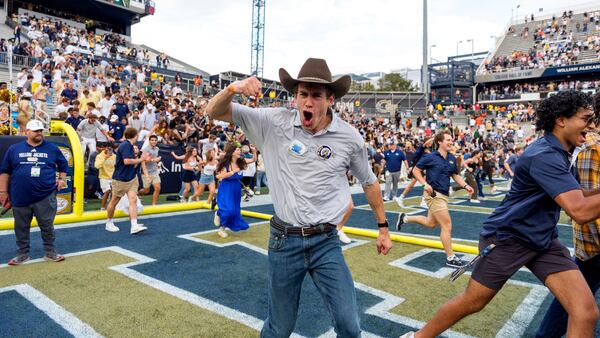 A Georgia Tech fan cheers as fans rush the field following an NCAA football game against Miami, Saturday, Nov. 9, 2024, in Atlanta. (AP Photo/Jason Allen)