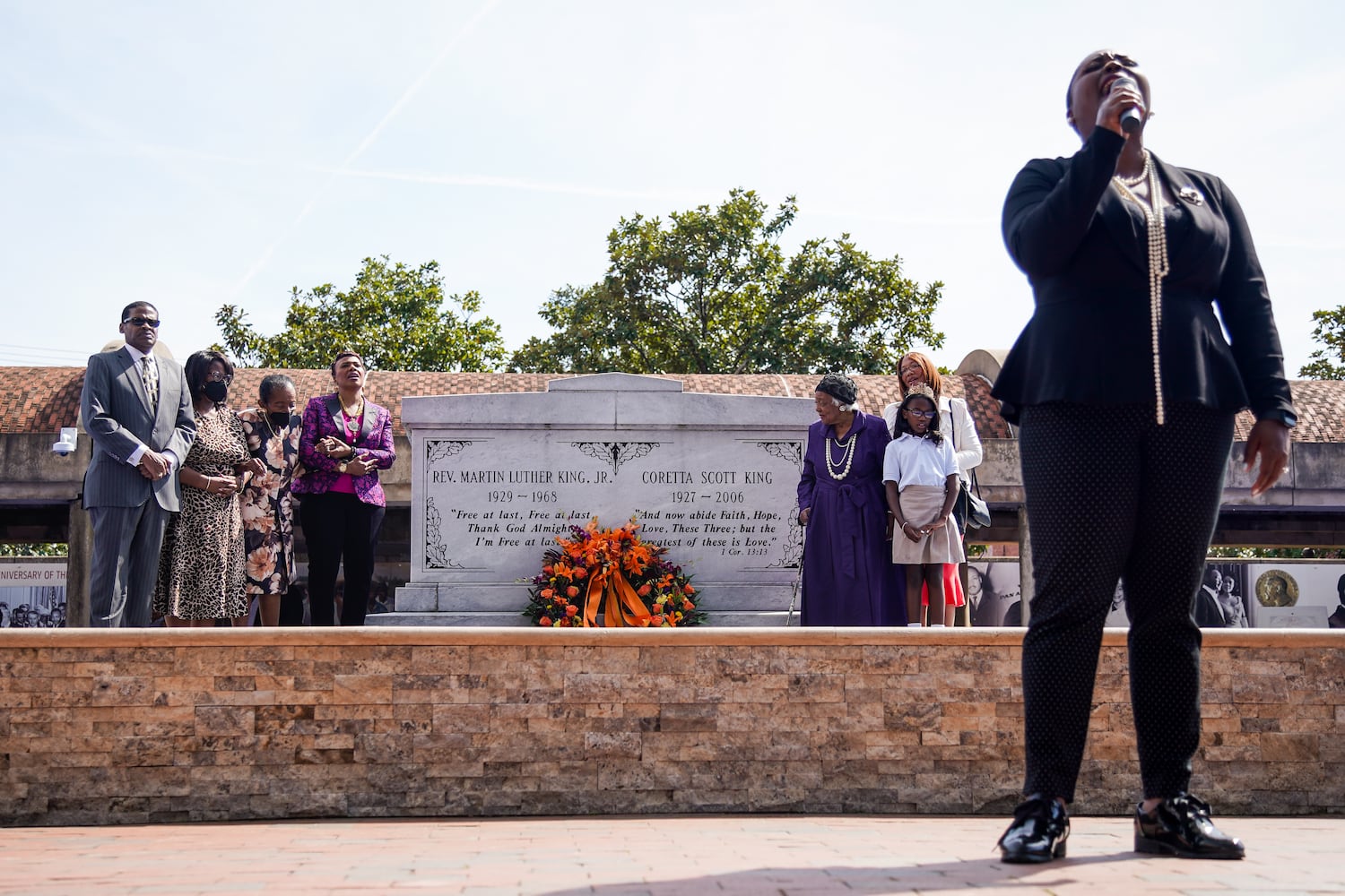 A woman sings 'We Shall Ovecome' after a wreath is laid in front of the tomb of Dr. Martin Luther King Jr. and Coretta Scott King as members of the King family flank the tomb at The King Center on the 54th anniversary of the assassination of Dr. Martin Luther King Jr., on Monday, April 4, 2022, in Atlanta. (Elijah Nouvelage/Special to the Atlanta Journal-Constitution)