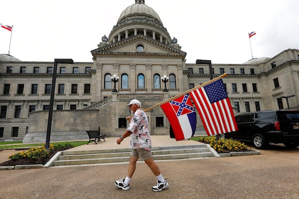 Don Hartness of Ellisville, walks around the Capitol carrying the current Mississippi state flag and the American flag, Saturday, June 27, 2020, in Jackson, Miss. A supporter of the current flag, Hartness wanted to make his position known to lawmakers as he walked around the building for several hours. The current state flag has in the canton portion of the banner the design of the Civil War-era Confederate battle flag, that has been the center of a long-simmering debate about its removal or replacement. (AP Photo/Rogelio V. Solis)