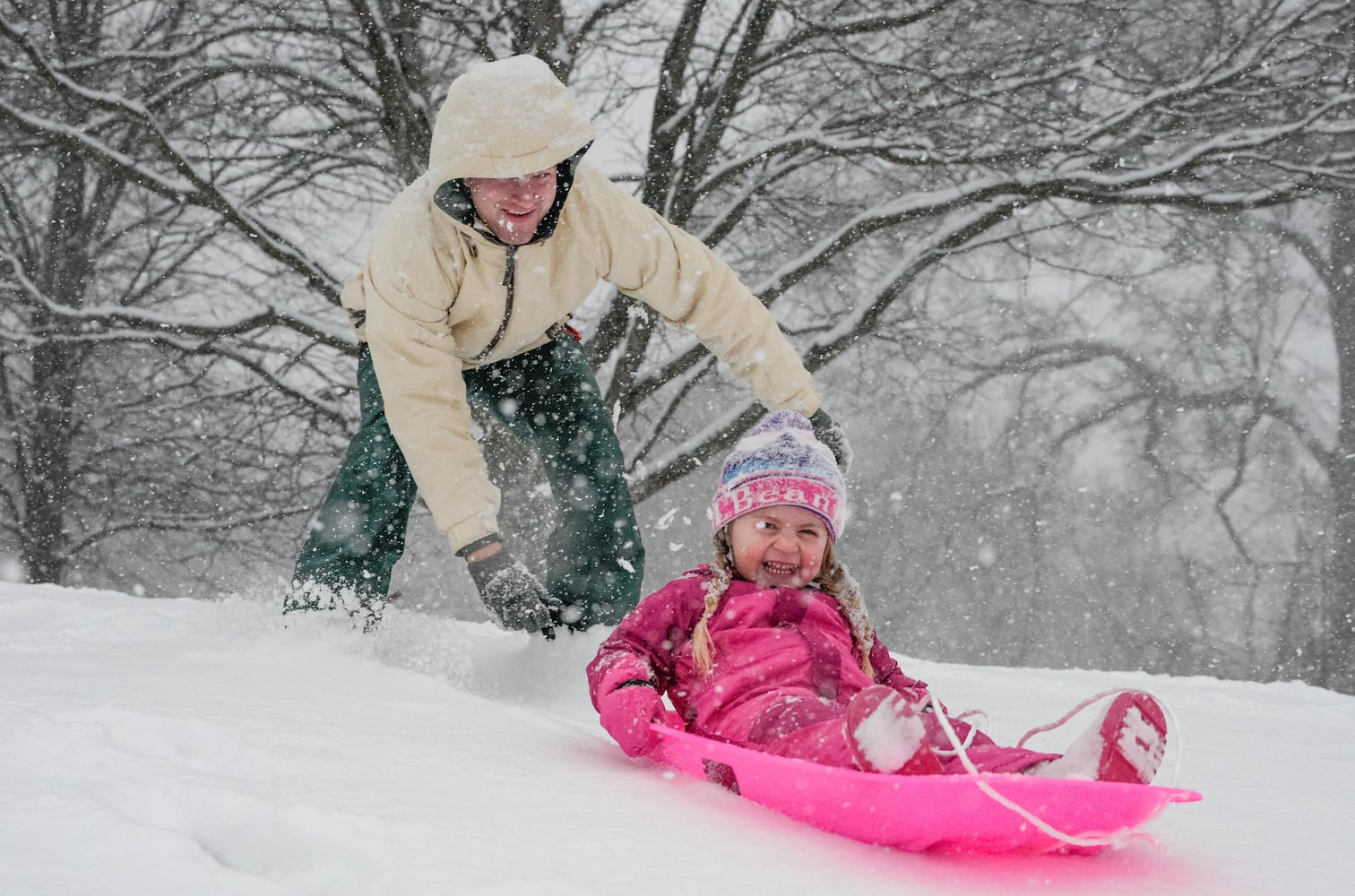 Tim Covacs pushes his three year old daughter Grey down a hill in Piedmont Park. Friday, January 10, 2025 (Ben Hendren for the Atlanta Journal-Constitution)