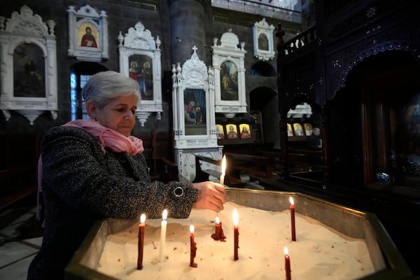 A Syrian woman lights a candle inside a church during the first Sunday Mass since Syrian President Bashar Assad's ouster, in old Damascus, Syria, Sunday, Dec. 15, 2024. (AP Photo/Hussein Malla)