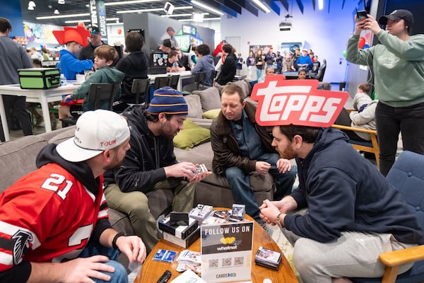 Avi Ghlzadeh, second from left, attracts a lot of attention as he goes through the cards in a just-opened Panini Noir NBA trading card box he bought for just over $2,000 at the CardsHQ store in Atlanta. Ben Gray for the Atlanta Journal-Constitution