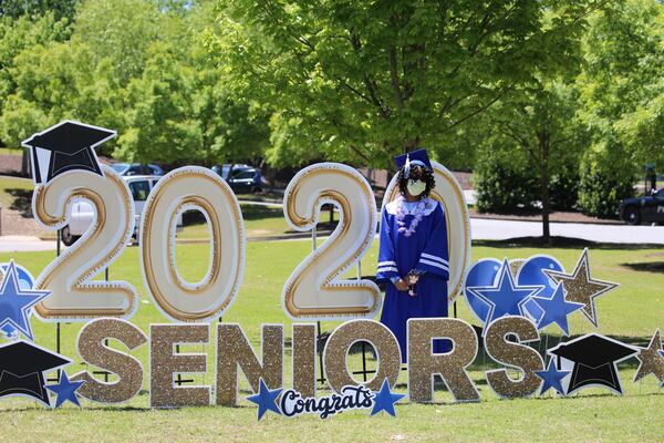 A McEachern High School graduate stands next to a sign congratulating seniors.