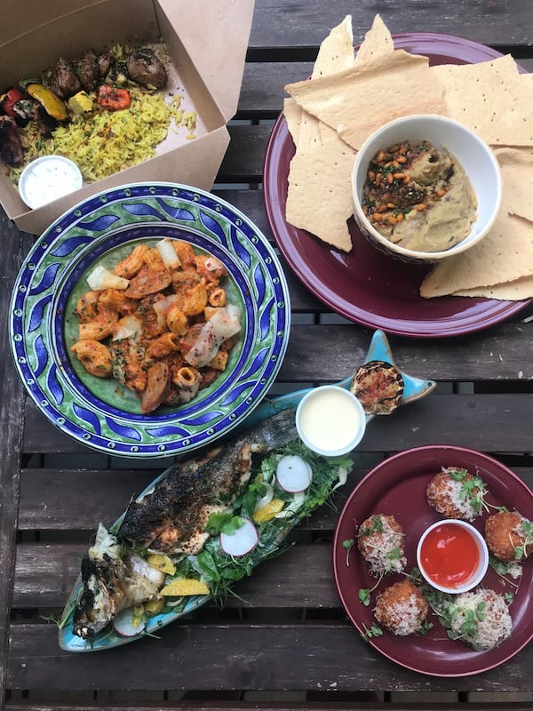 The menu at Fia is Mediterranean-focused. Pictured (clockwise from top left) are: lamb kebabs with saffron orange basmati rice, wood-fired hummus with lavash, tomato risotto arancini, grilled whole branzino with fennel-citrus salad, and handmade rigatoni. LIGAYA FIGUERAS / LIGAYA.FIGUERAS@AJC.COM