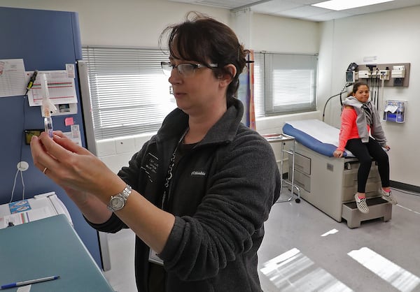 Kristen Earley, a nurse at the Clark County Combined Health District, gets a flu shot ready at the Health District offices. BILL LACKEY/STAFF