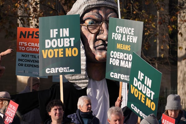 Protesters show placards in front of Parliament in London, Friday, Nov. 29, 2024 as British lawmakers started a historic debate on a proposed to help terminally ill adults end their lives in England and Wales.(AP Photo/Alberto Pezzali)