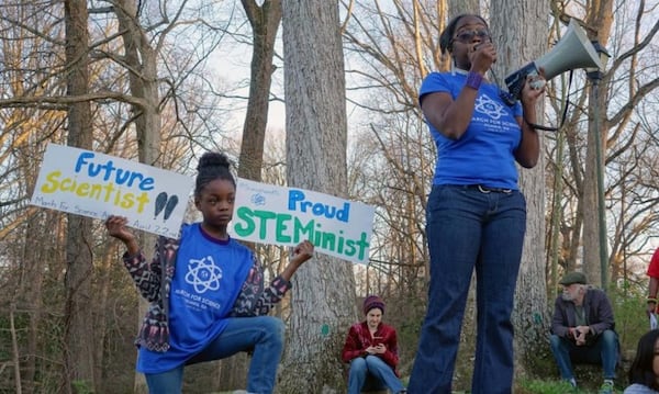 Dr. Jasmine Clark, a microbiologist who organized the Atlanta March for Science, promoted the Earth Day march at a women’s rally on March 8 at Candler Park. Her 8-year-old daughter, Jayda, held signs nearby.