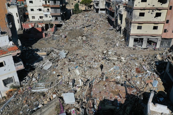 Residents walk on the rubble of destroyed buildings after they returned to Qana village, southern Lebanon, Thursday, Nov. 28, 2024 following a ceasefire between Israel and Hezbollah that went into effect on Wednesday.(AP Photo/Hussein Malla)