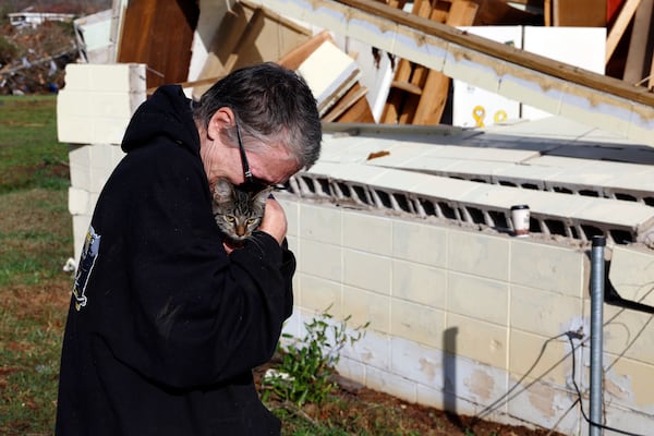 Emily Robertson reunites with one of her cats as she looks for personal belongings in the damage after a tornado passed through where two people lost their lives, Sunday, March 16, 2025, in Plantersville, Ala. (AP Photo/Butch Dill)