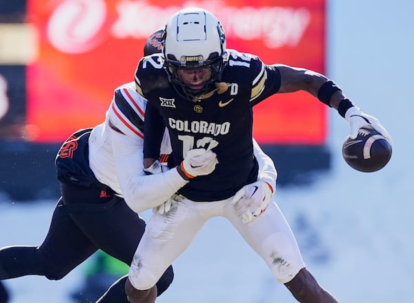 FILE - Colorado wide receiver Travis Hunter, front, is tackled after pulling in a pass by Oklahoma State safety Kobe Hylton in the first half of an NCAA college football game Friday, Nov. 29, 2024, in Boulder, Colo. (AP Photo/David Zalubowski, File)