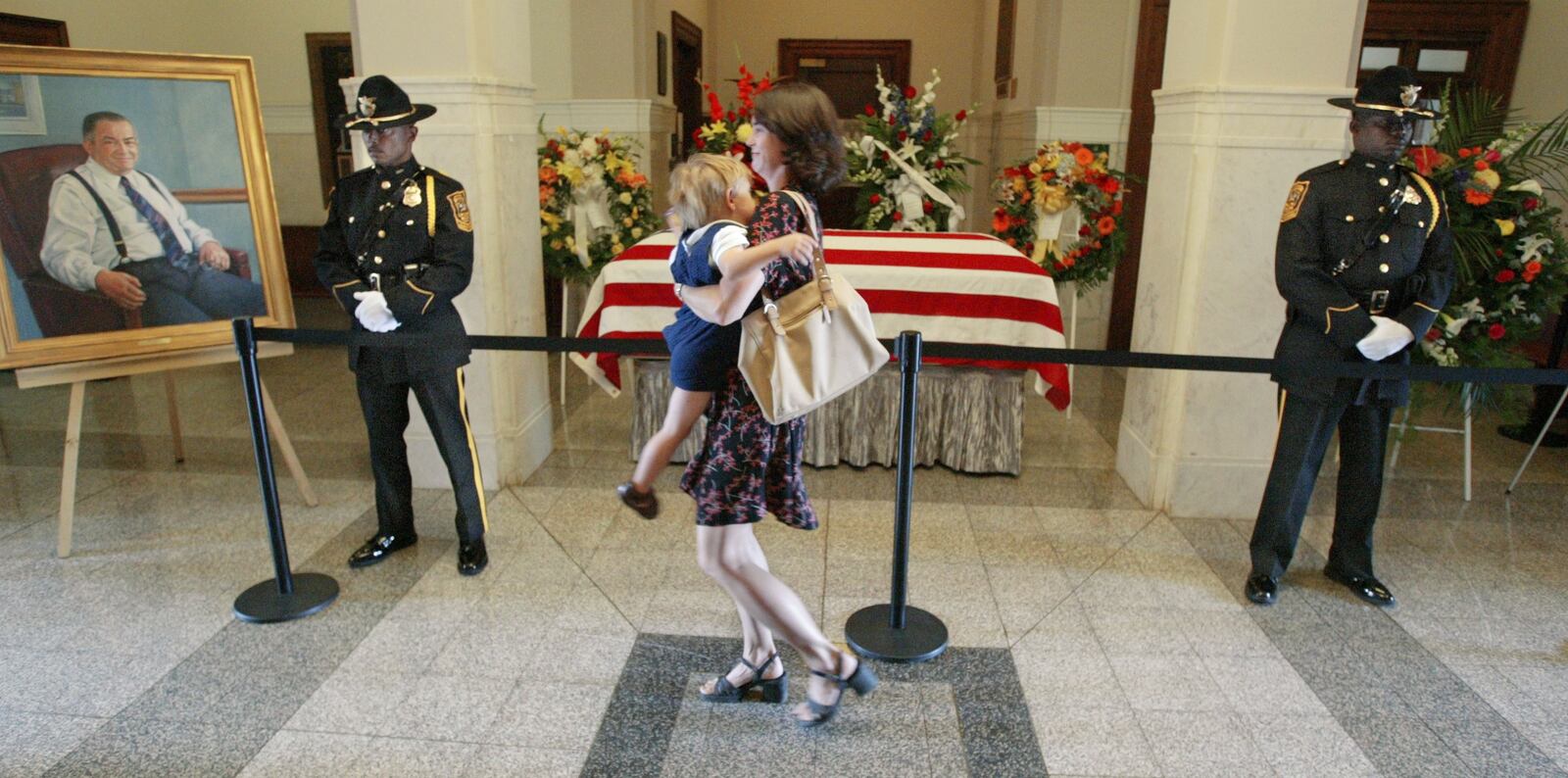 040811- DECATUR/DEKALB COUNTY, GA -- DeKalb County Police honor guards officer, Donald Berry (cq)(left) and officer, Terry White (cq)(right) stand at attention as state representative, Stephanie Stuckey Benfield holds son, Robert-2 (cq) as she pays respects to Manuel Maloof lying in state. Rep. Benfield says Maloof was a great man and had helped her, and many other new candidates breaking into politics by his advice and support. The former DeKalb County chief executive officer and commission chairman, Manuel J. Maloof's body lay in state at the Old County Courthouse in Decatur Wednesday where the public was welcomed. The funeral will be noon Thursday at All Saints Catholic Church in Dunwoody. (JOHN SPINK/AJC staff)