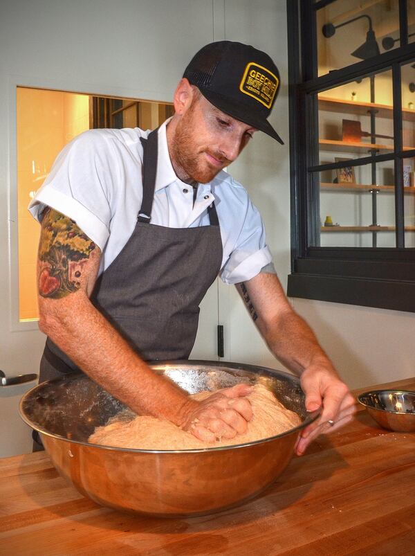 Chris Wilkins kneads a batch of whole wheat dough in the baking area of Root Baking Co. “One of the tricks to hand-kneading dough as a business owner and baker is to always have a clean hand to answer the phone when it rings,” he said. CONTRIBUTED BY CHRIS HUNT / SPECIAL