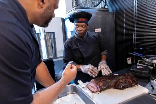 Greg Dennis, executive chef for J’s Smokehouse, prepares brisket during a training session with certified master chief Daryl Shular (left) in Atlanta on Wednesday, August 28, 2024. (Arvin Temkar / AJC)