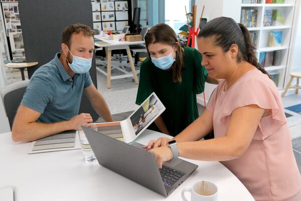 Shelby Eanes, center, an account executive, works with clients Andrew Pletcher, left, and Karla Orellana, right, on designing a corporate space at Interface’s headquarters in Atlanta on Tuesday. Interface is an Atlanta-based flooring company. With workers coming back into the office, tools such as collaboration areas, focus rooms and a desk reservation system are being used to ensure the safety and social distancing of employees. (Christine Tannous / christine.tannous@ajc.com)