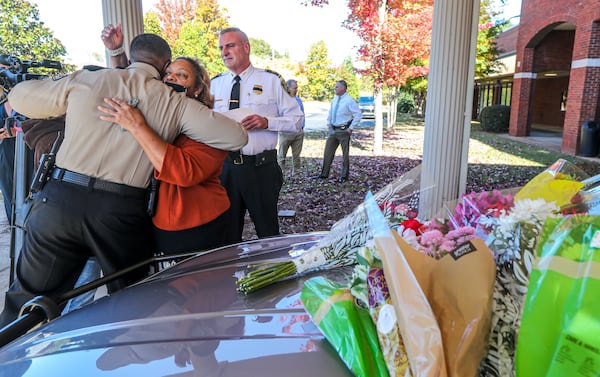 Henry County Chairperson, Carlotta Harrell hugs Henry County Sheriff Reginald Scandrett (left) as Henry County Police Chief, Mark Amerman (right) looks on before the police cruiser belonging to fallen Officer Paramhans Desai. Henry County police held a press conference on Tuesday, Nov. 9, 2021, to update the public in regards to the death of Paramhans Desai. Funeral arrangements for Desai were pending Tuesday. (John Spink / John.Spink@ajc.com)



