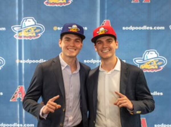 Twin brothers Stefan Caray (left, in blue cap) and Chris Caray (right, in red cap) after a press conference introducing them as the broadcasters for the Amarillo Sod Poodles minor-league baseball team.  (Photo by Isaac Galan / Special to the AJC)