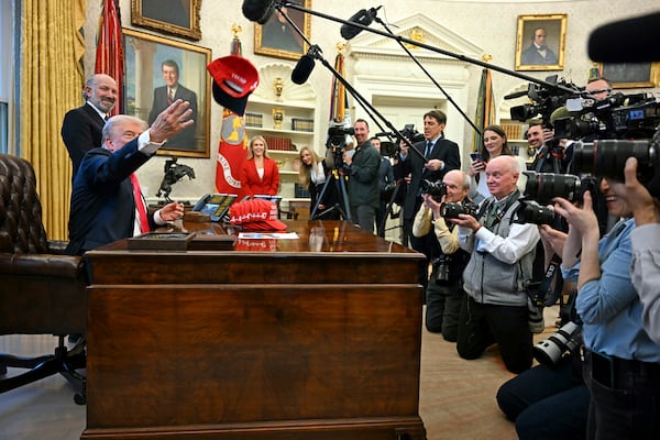 President Donald Trump throws a hat that reads "Trump was right about everything" as he talks to reporters in the Oval Office at the White House on Tuesday.