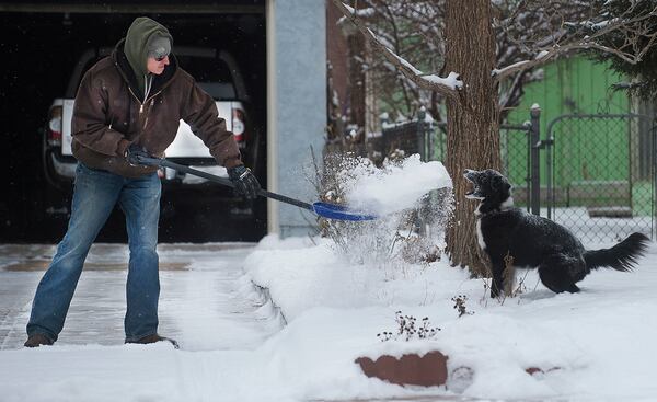 Zach Starcer tosses a shovel full of snow to his six-year-old boarder collie, Callie, while clearing the driveway in Pueblo, Colo., Thursday, Jan. 5, 2017 in Pueblo, Colo. Skiers throughout the West gleefully flocked to resorts Thursday to take advantage of deep, fresh snow dumped by a series of winter storms that were moving east and threatening turbulent weather across much of the Southwest. The storms pounded parts of California, Utah, Colorado and other states as they made their way east. (Bryan Kelsen/The Pueblo Chieftain via AP)