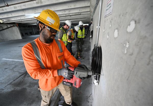 Pierre Richard Petit Frere, with EnviroSpark Energy Solutions, drills to install a EV cord holster for a 40 amp EV charger at LaVista Walk apartments, Friday, June 23, 2023, in Atlanta. (Hyosub Shin / Hyosub.Shin@ajc.com)