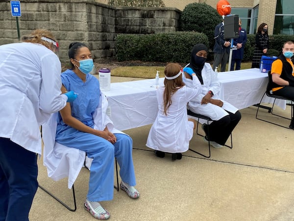 Dr. Gayla Dillard, seated at the far left, is a surgeon with Piedmont Healthcare.  She received her vaccination against COVID-19 Thursday, one of Piedmont's first five workers to be vaccinated.  Dr. Dillard has had to do surgery on one of her own friends seriously ill with the disease. (PHOTO by Ariel Hart / ahart@ajc.com)