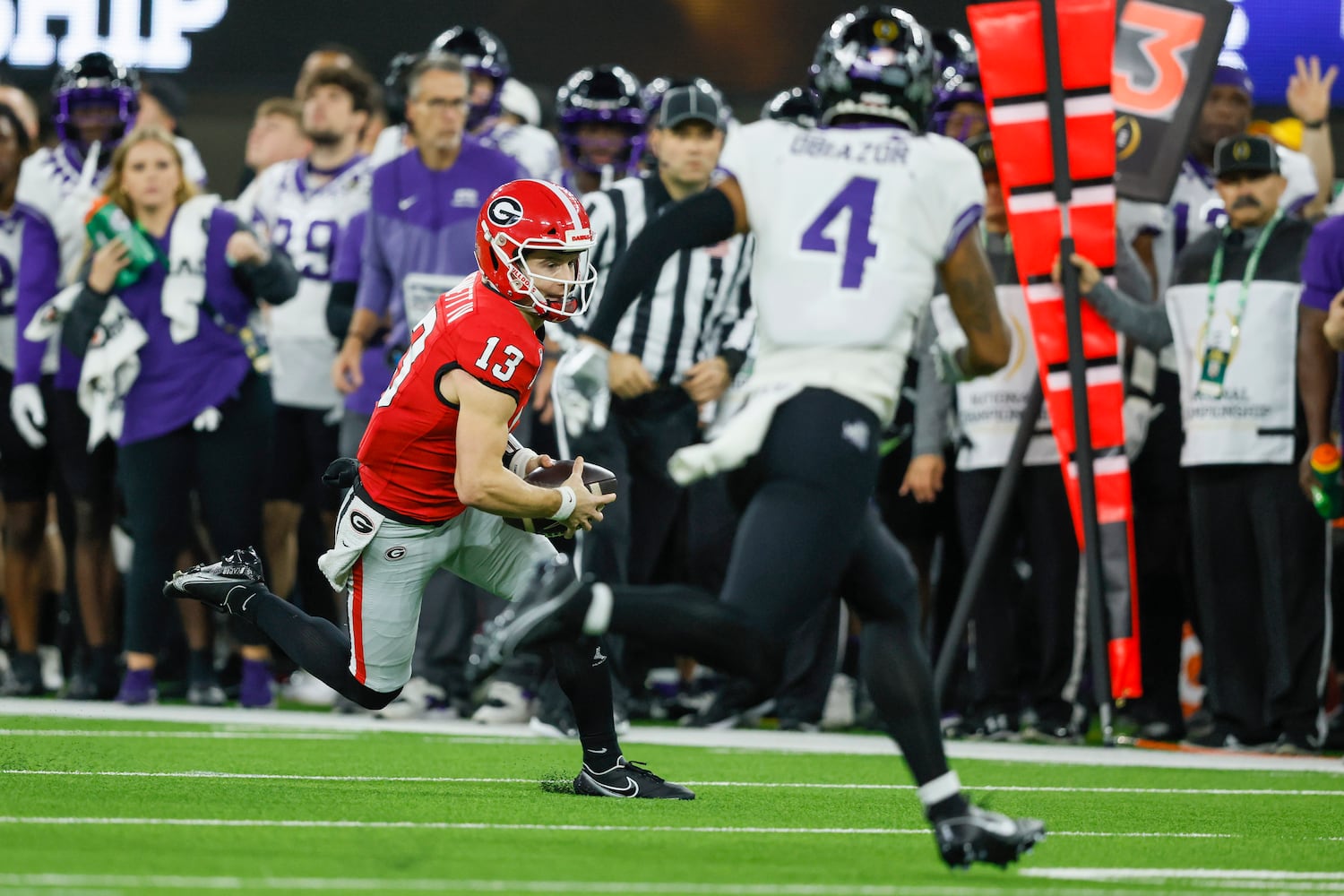 Georgia Bulldogs quarterback Stetson Bennett (13) runs a keeper play against TCU Horned Frogs safety Namdi Obiazor (4) during the first half of the College Football Playoff National Championship at SoFi Stadium in Los Angeles on Monday, January 9, 2023. (Jason Getz / Jason.Getz@ajc.com)