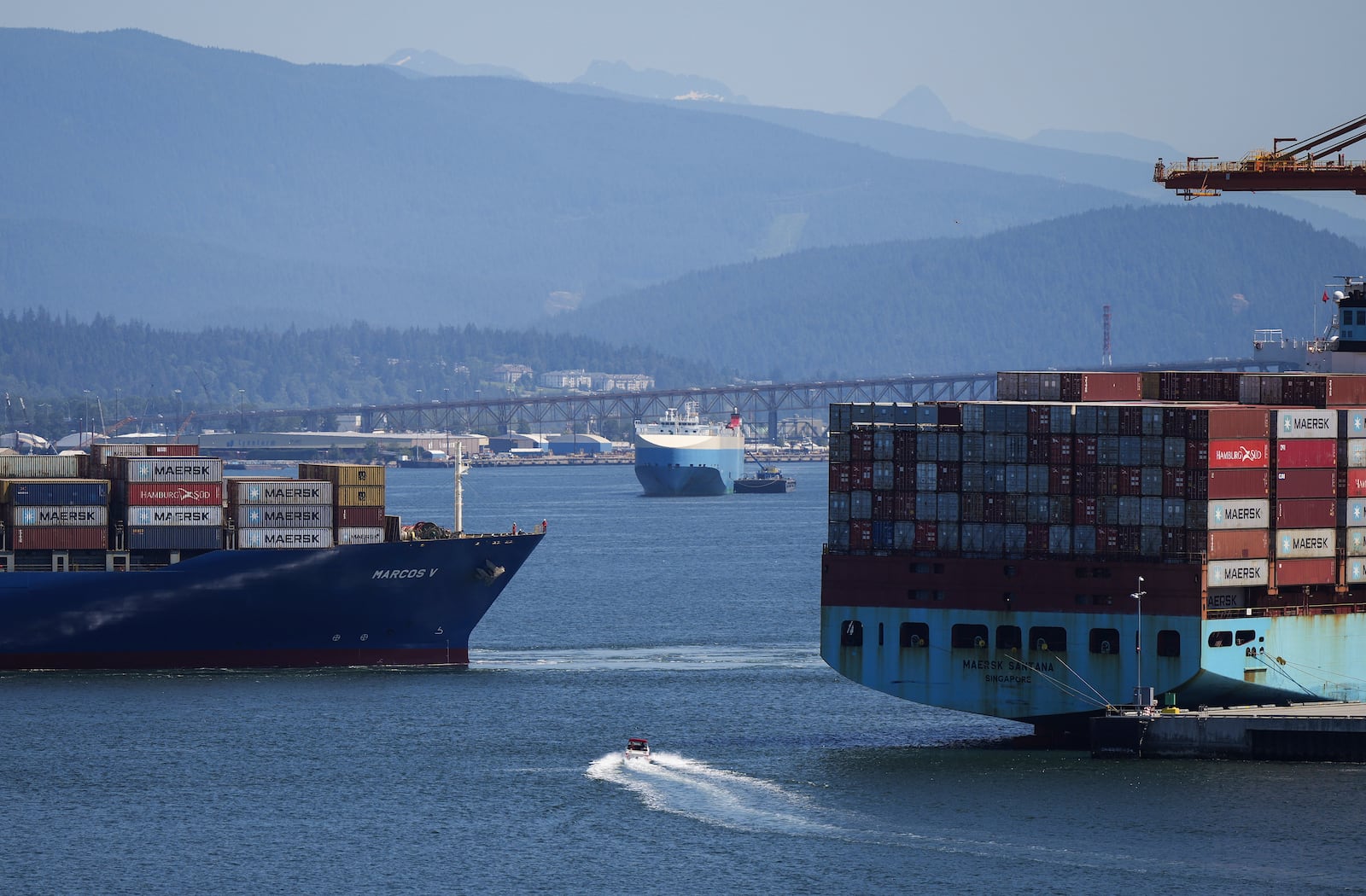 FILE - A boater passes between cargo ships on the harbor, in Vancouver, British Columbia, July 16, 2024. (Darryl Dyck/The Canadian Press via AP, File)