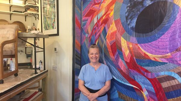 Artist Char Downs, who moved to Paducah from the San Francisco area as part of the city&apos;s artist relocation program, stands in her studio by her painting of Caryl Bryer Fallert-Gentry&apos;s quilt titled Corona II: Solar Eclipse. (Lori Rackl/Chicago Tribune/TNS)