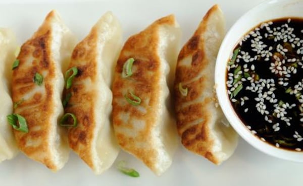 Pan-fried pork dumplings are served with a sesame sauce.