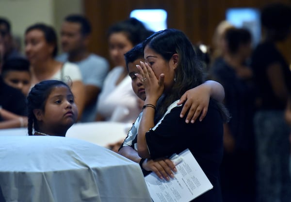 Family members mourn in front of the caskets of the victims, Martin Romero, 33, and four of his children, before their funeral mass for at St. Lawrence Catholic Church in Lawrenceville on Thursday, July 13, 2017. HYOSUB SHIN / HSHIN@AJC.COM