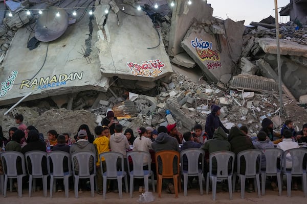 Palestinians sit at a large table surrounded by the rubble of destroyed homes and buildings as they gather for iftar, the fast-breaking meal, on the first day of Ramadan in Rafah, southern Gaza Strip, Saturday, March 1, 2025 (AP Photo/Abdel Kareem Hana)