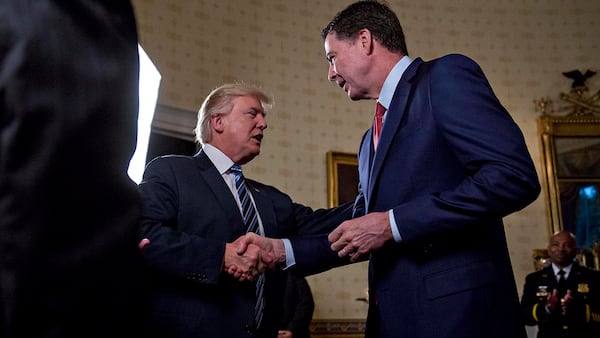 WASHINGTON, DC - JANUARY 22: U.S. President Donald Trump (C) shakes hands with James Comey, director of the Federal Bureau of Investigation (FBI), during an Inaugural Law Enforcement Officers and First Responders Reception in the Blue Room of the White House on January 22, 2017 in Washington, DC. Trump today mocked protesters who gathered for large demonstrations across the U.S. and the world on Saturday to signal discontent with his leadership, but later offered a more conciliatory tone, saying he recognized such marches as a "hallmark of our democracy." (Photo by Andrew Harrer-Pool/Getty Images)