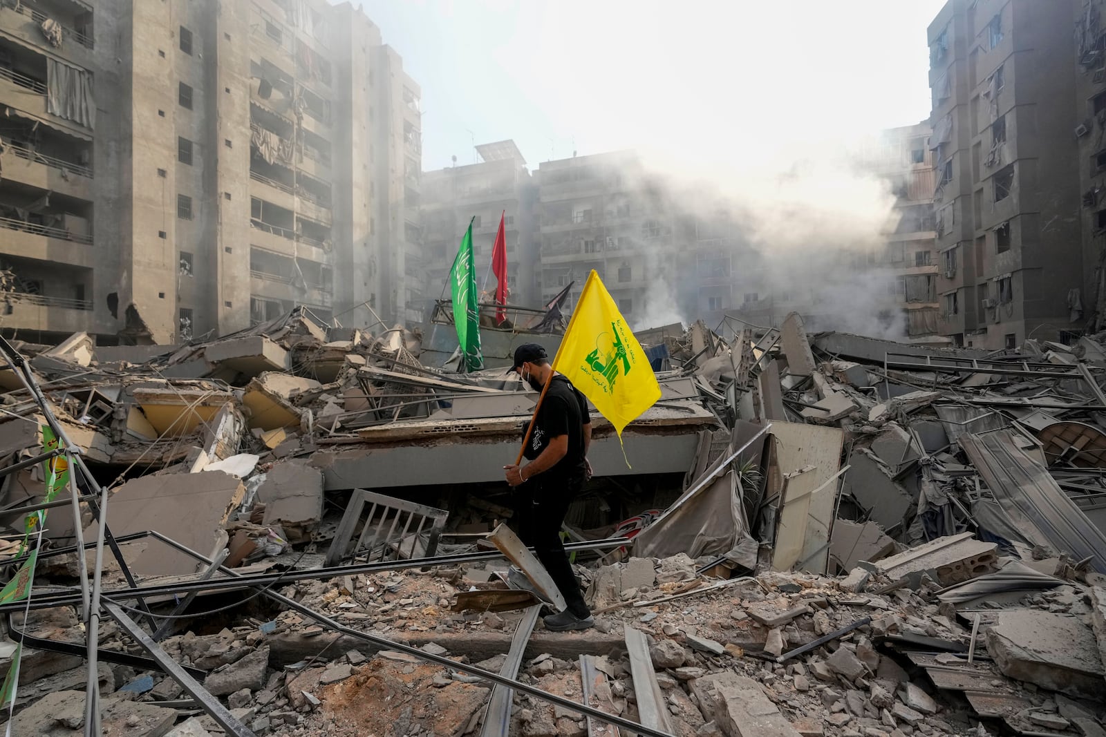 A man carries a Hezbollah flag as he walks on the rubble of his destroyed apartment following an Israeli airstrike in Dahiyeh, Beirut, Lebanon, Friday, Nov. 1, 2024. (AP Photo/Hassan Ammar)