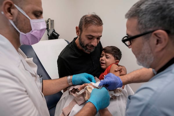 Hassan Mikdad, holds his son Hussein Mikdad, 4, who was injured on Oct. 2 in an Israeli airstrike at a densely-populated neighborhood south of Beirut, during a check up by his doctor at the American University of Beirut Medical Center (AUBMC), in Beirut, Lebanon, Tuesday, Nov. 5, 2024. (AP Photo/Bilal Hussein)